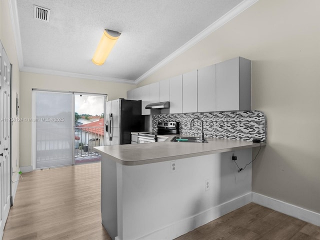 kitchen with lofted ceiling, under cabinet range hood, fridge with ice dispenser, stainless steel range with electric stovetop, and a sink