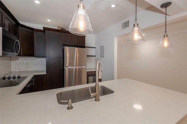 kitchen featuring pendant lighting, visible vents, appliances with stainless steel finishes, a sink, and dark brown cabinets