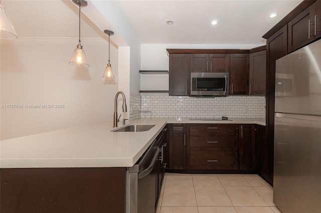 kitchen with dark brown cabinetry, tasteful backsplash, stainless steel appliances, light countertops, and a sink