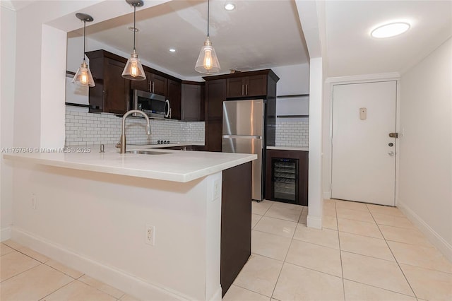 kitchen with light tile patterned floors, dark brown cabinetry, stainless steel appliances, a peninsula, and a sink