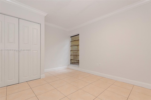 unfurnished bedroom with ornamental molding, a closet, baseboards, and light tile patterned floors