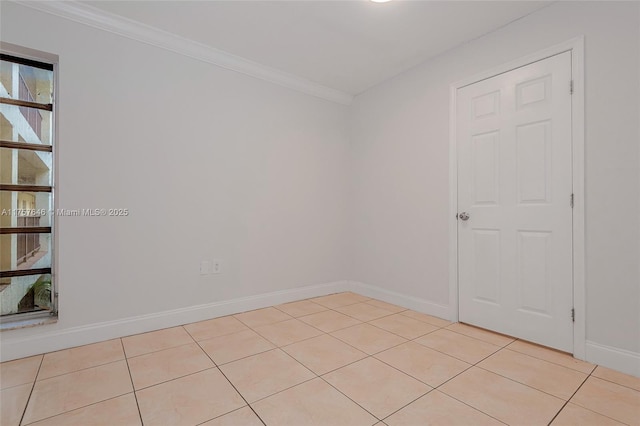 spare room featuring light tile patterned floors, ornamental molding, and baseboards