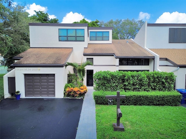 view of front of property featuring a shingled roof, a front yard, aphalt driveway, and stucco siding