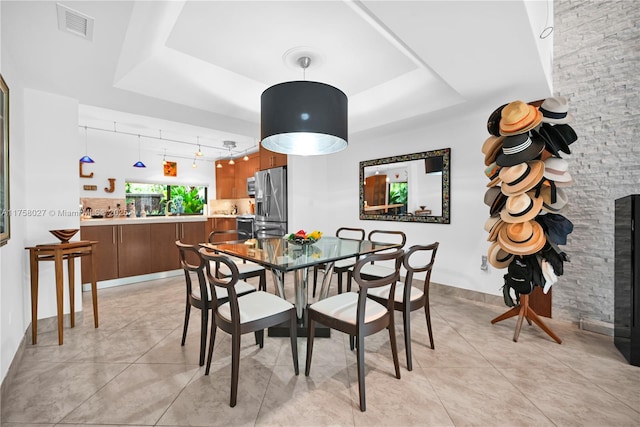 dining room with a raised ceiling, visible vents, and light tile patterned floors