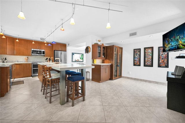 kitchen with stainless steel appliances, backsplash, visible vents, and brown cabinets