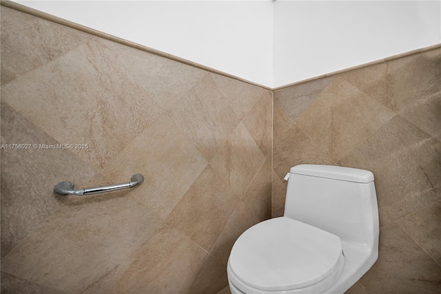 bathroom featuring toilet and tile walls