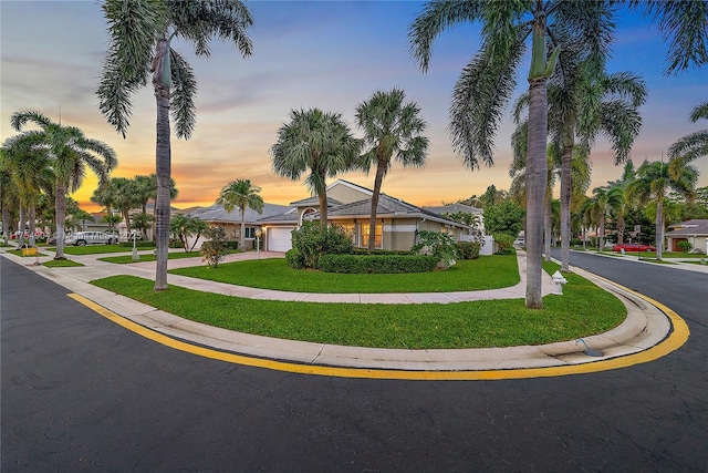 view of front of home with concrete driveway, a lawn, and an attached garage