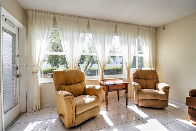 sitting room with a wealth of natural light, a textured ceiling, baseboards, and light tile patterned floors