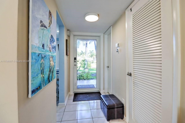 doorway to outside with light tile patterned flooring and baseboards