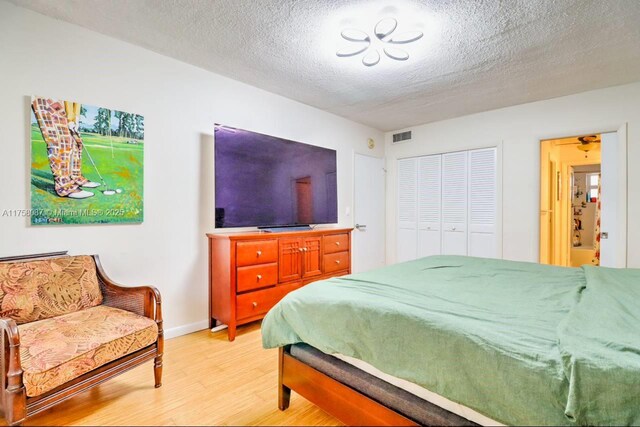 850 NE 12th Ave Unit 210, Hallandale Beach, FL 33009 - bedroom featuring a closet, light wood finished floors, a textured ceiling, baseboards, and visible vents