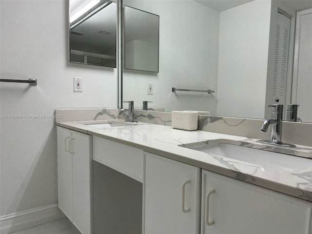 bathroom with double vanity, a sink, and baseboards