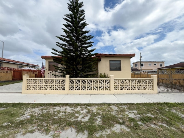 view of front facade featuring a tile roof, fence, and stucco siding