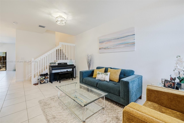 living room with light tile patterned floors, visible vents, stairway, and baseboards