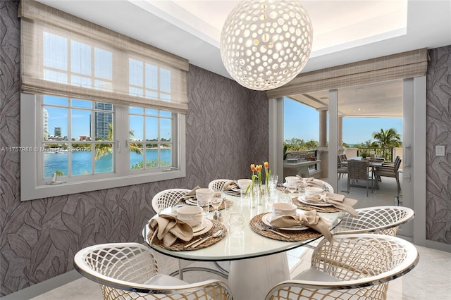 dining space featuring wallpapered walls, a tray ceiling, and an inviting chandelier