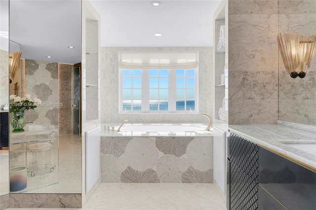 bathroom featuring a garden tub, recessed lighting, tile walls, and vanity