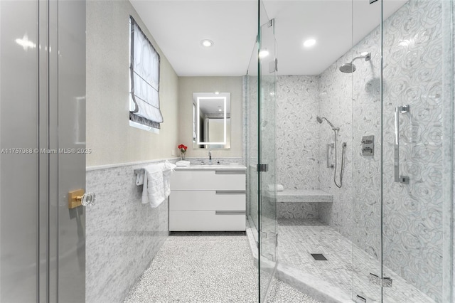 full bath with wainscoting, vanity, a shower stall, tile walls, and recessed lighting