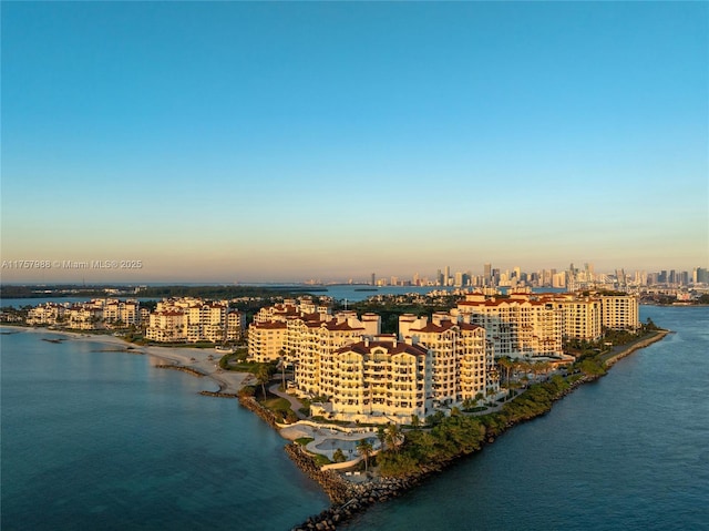 aerial view at dusk featuring a water view and a city view