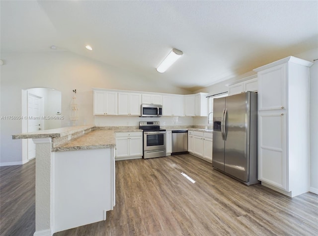 kitchen with lofted ceiling, stainless steel appliances, a peninsula, and light countertops