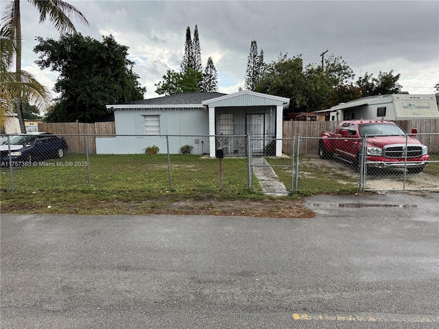 view of front facade with a front lawn, a fenced front yard, and a gate