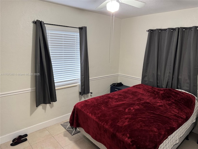 tiled bedroom with ceiling fan and baseboards