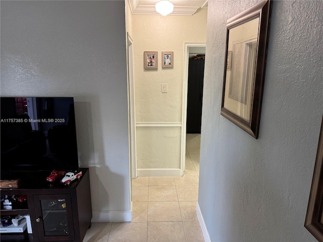 hall featuring tile patterned flooring, baseboards, and a textured wall