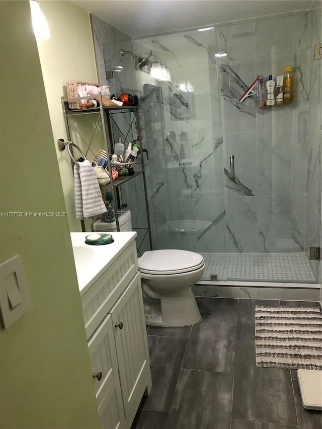 bathroom featuring vanity, a marble finish shower, and toilet