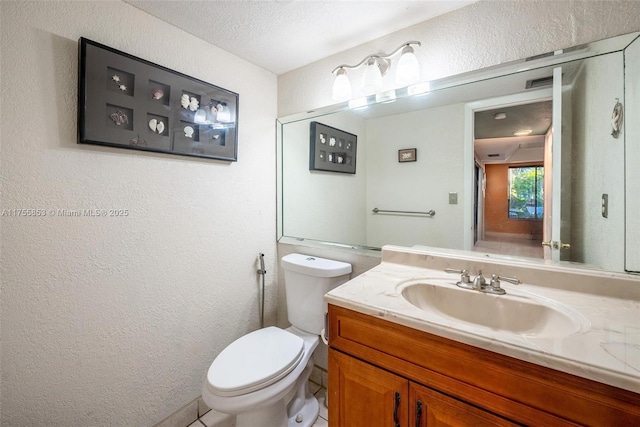 bathroom featuring a textured wall, vanity, and toilet