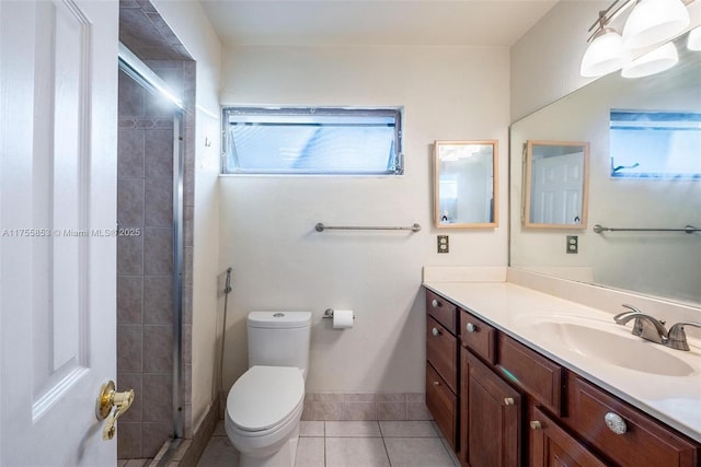 full bath featuring tile patterned flooring, toilet, vanity, baseboards, and a shower stall