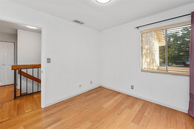 empty room featuring visible vents, baseboards, and wood finished floors