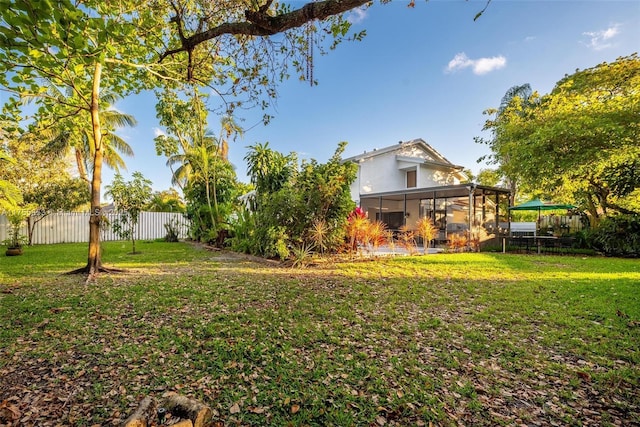 view of yard featuring a sunroom and a fenced backyard