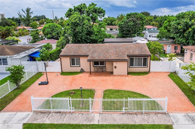 view of front of house with stucco siding, a gate, a fenced backyard, a front yard, and a patio area