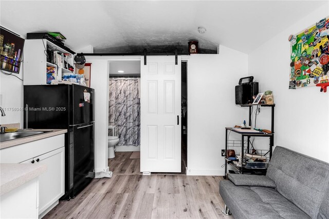 6830 SW 5th Ter, Miami, FL 33144 - kitchen with light wood-type flooring, a barn door, vaulted ceiling, white cabinetry, and a sink