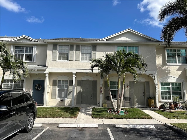 townhome / multi-family property featuring uncovered parking and stucco siding