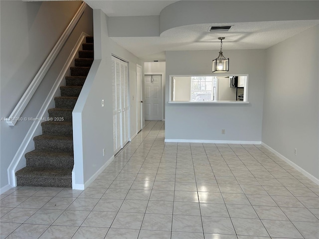 spare room featuring stairway, visible vents, and baseboards