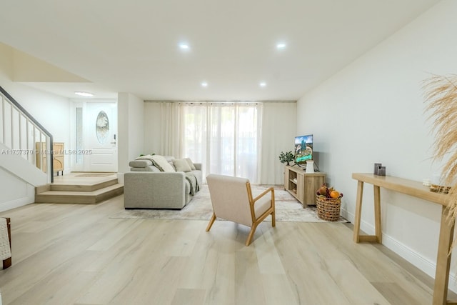 living area featuring recessed lighting, light wood-style flooring, baseboards, and stairs