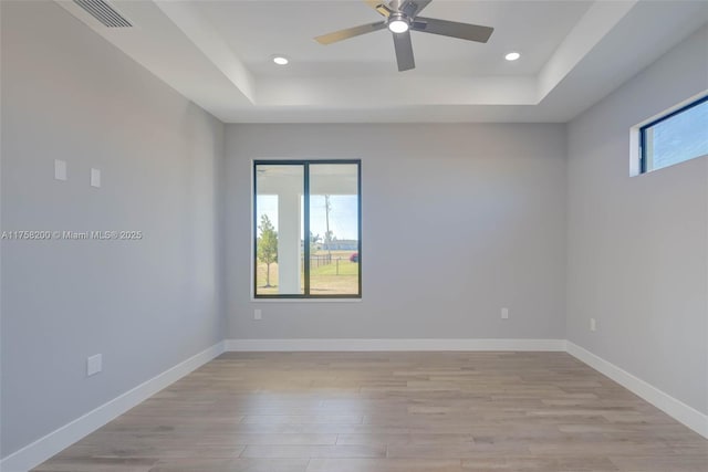 empty room with a healthy amount of sunlight, baseboards, and a raised ceiling