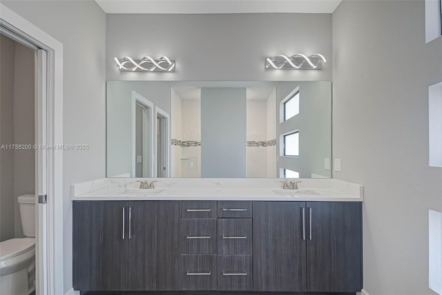 full bathroom with double vanity, a sink, and toilet