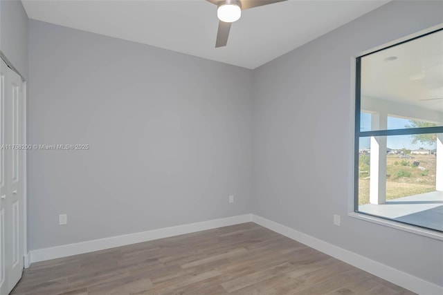 empty room with ceiling fan, wood finished floors, and baseboards