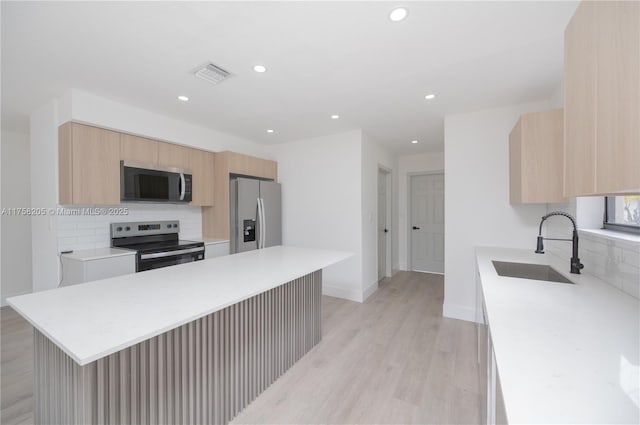 kitchen featuring stainless steel appliances, visible vents, light brown cabinets, and light countertops