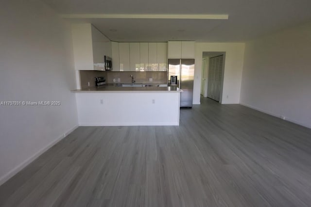 kitchen with stainless steel appliances, tasteful backsplash, open floor plan, white cabinetry, and a peninsula