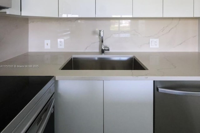 kitchen featuring tasteful backsplash, range, a sink, white cabinetry, and stainless steel dishwasher