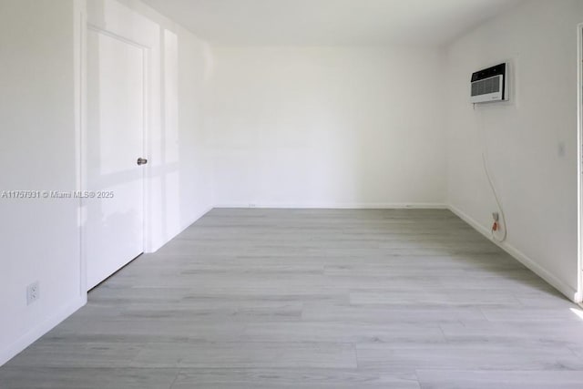 empty room featuring light wood finished floors and a wall mounted AC