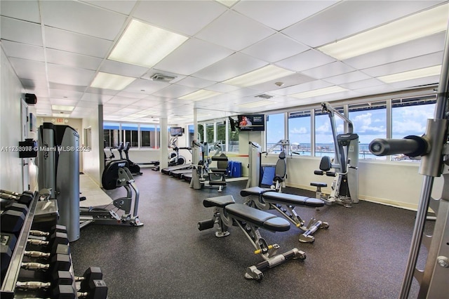 workout area with a drop ceiling, visible vents, and baseboards