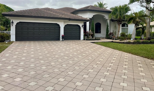 view of front facade with decorative driveway, an attached garage, and stucco siding