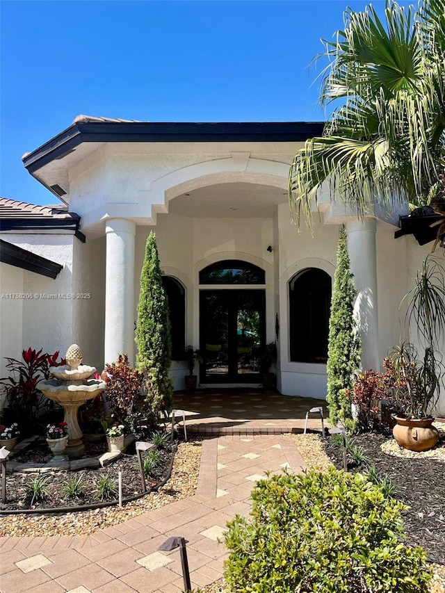 doorway to property with a tiled roof, stucco siding, and french doors