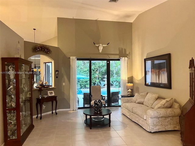 living area with high vaulted ceiling, baseboards, visible vents, and light tile patterned flooring