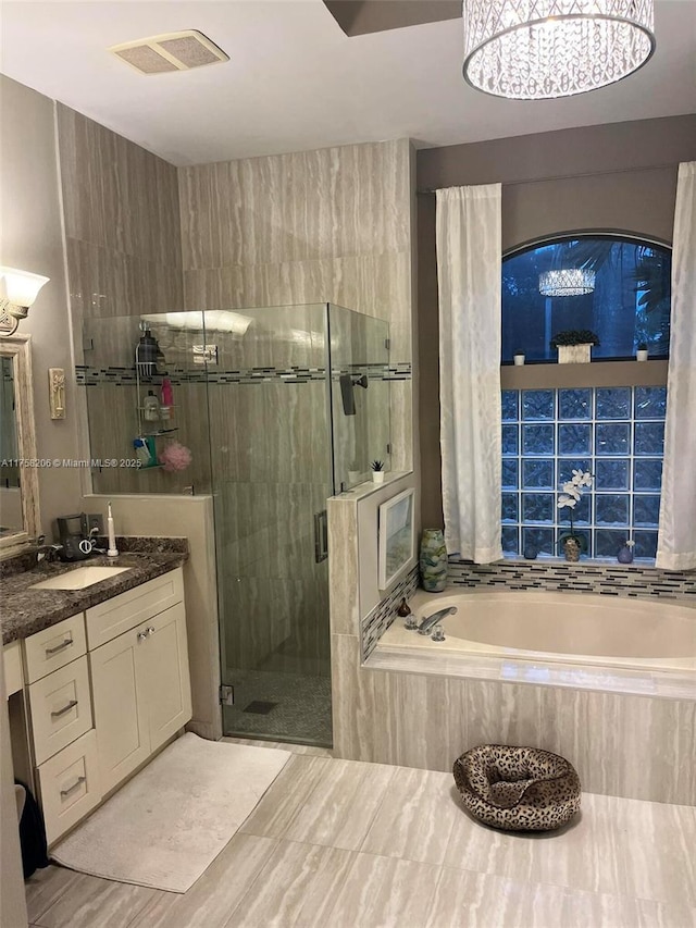 bathroom with vanity, a stall shower, a garden tub, and visible vents