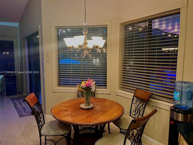 tiled dining area with lofted ceiling, a notable chandelier, and baseboards