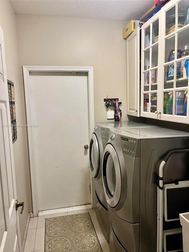 laundry room featuring light tile patterned floors, a textured ceiling, independent washer and dryer, and cabinet space