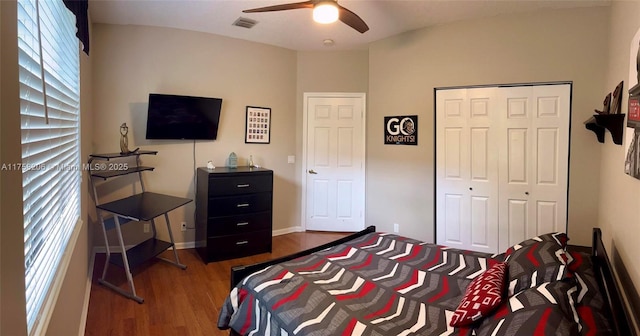 bedroom featuring wood finished floors, visible vents, baseboards, a ceiling fan, and a closet